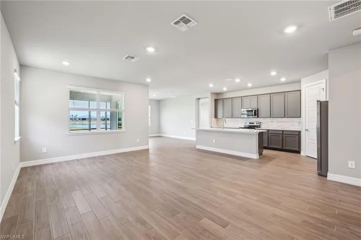 Kitchen with stainless steel appliances, open floor plan, a sink, light wood-style flooring, and recessed lighting