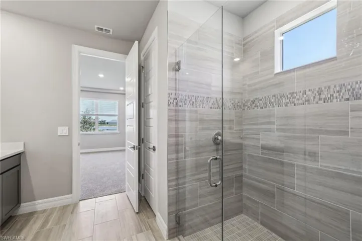 Full bath with vanity, baseboards, and a shower stall