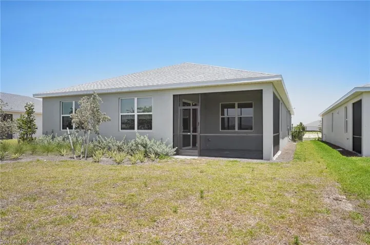 Back of house featuring a sunroom, stucco siding, a yard, and roof with shingles