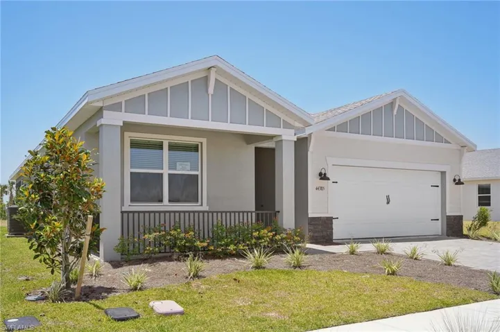 View of front of property with board and batten siding, a porch, an attached garage, driveway, and a front lawn
