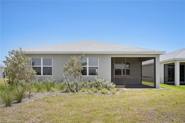 Back of property featuring a sunroom, stucco siding, and a lawn