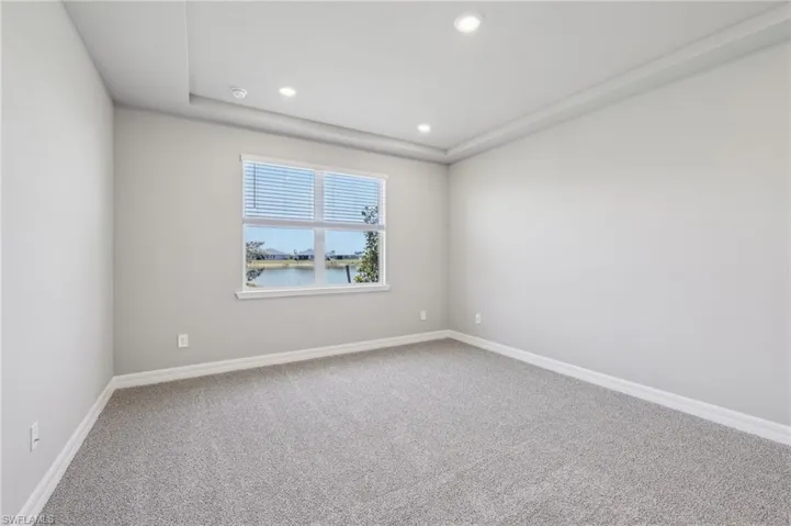 Carpeted spare room with recessed lighting, baseboards, and a water view