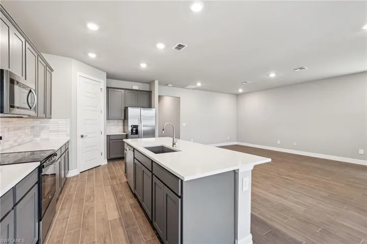 Kitchen featuring a sink, appliances with stainless steel finishes, gray cabinets, light wood-type flooring, and recessed lighting