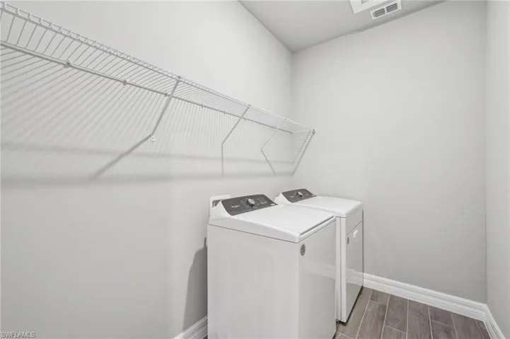 Laundry room with separate washer and dryer, baseboards, and wood tiled floors