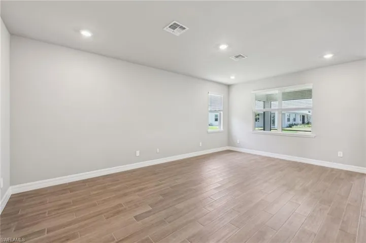 Spare room with light wood-style floors, baseboards, and recessed lighting