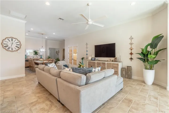 Living room featuring ornamental molding, recessed lighting, ceiling fan, and stone tile flooring