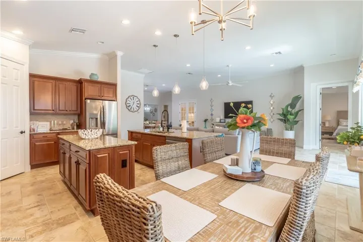 Dining area with ornamental molding, a chandelier, recessed lighting, stone tile flooring, and ceiling fan