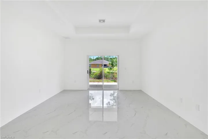 Spare room with light marble finish flooring and a raised ceiling