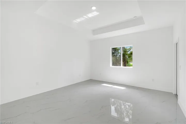Spare room with light marble finish flooring and a tray ceiling