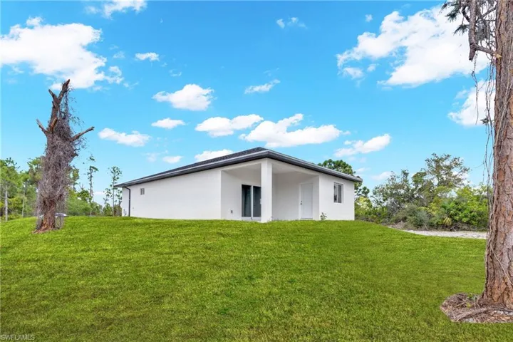 Back of house with a lawn and stucco siding
