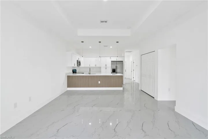 Unfurnished living room with a raised ceiling and recessed lighting