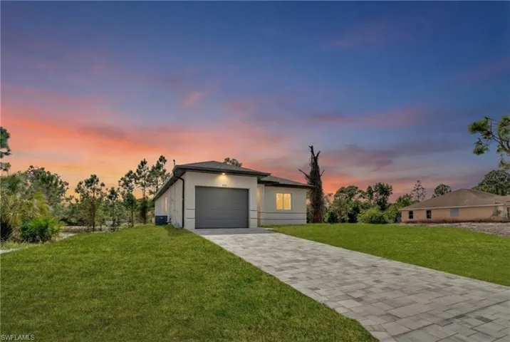 View of front facade with a front yard, decorative driveway, and stucco siding
