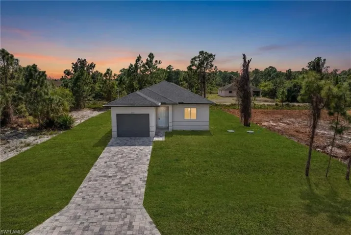 View of front of property featuring a yard, driveway, a garage, and roof with shingles