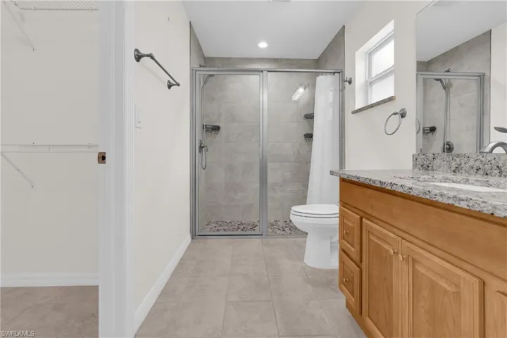 Master bathroom featuring a walk in closet, a stall shower, vanity, and light tile patterned floors