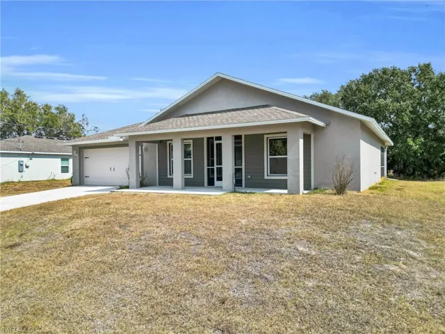 View of front facade featuring an attached garage, a shingled roof, stucco siding, concrete driveway, and a front lawn