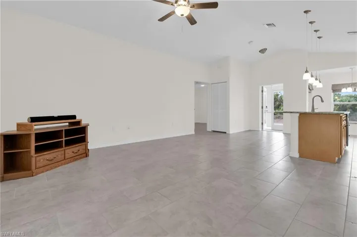 living room with vaulted ceiling, ceiling fan, light tile patterned floors, and a chandelier