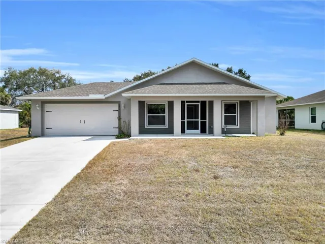 Ranch-style home with stucco siding, a shingled roof, concrete driveway, a front lawn, and an attached garage