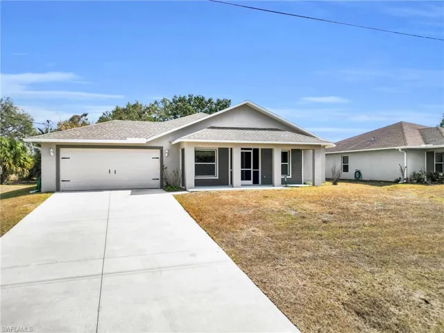 Ranch-style home featuring a front yard, stucco siding, concrete driveway, and an attached garage