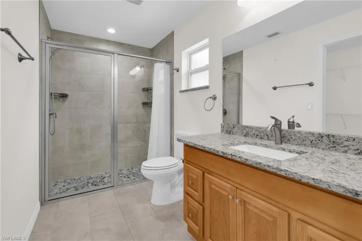 Master Bathroom featuring a shower stall, a spacious closet, vanity, and light tile patterned flooring