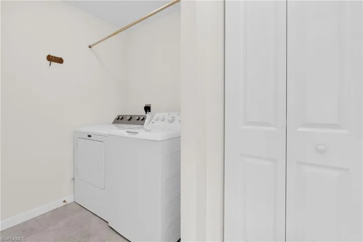 Laundry room with separate washer and dryer and light tile patterned floors