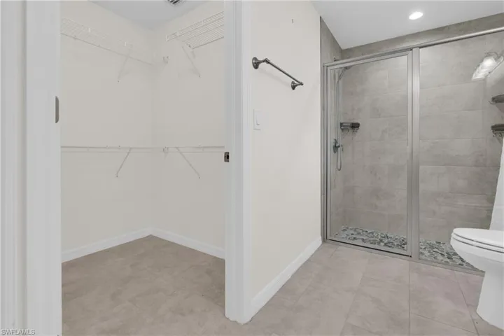 Master Bathroom with a walk in closet, a stall shower, recessed lighting, and light tile patterned floors
