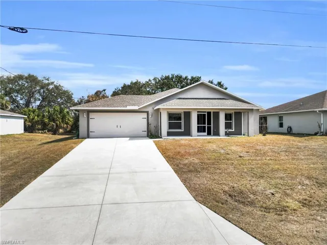 Single story home featuring a front lawn, roof with shingles, concrete driveway, an attached garage, and stucco siding
