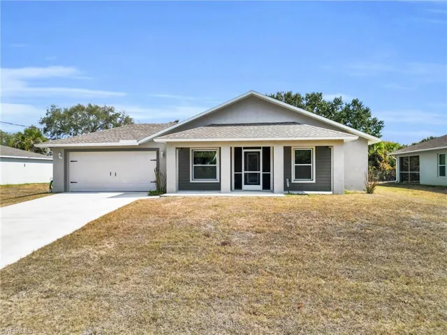 Single story home featuring a front yard, stucco siding, and driveway