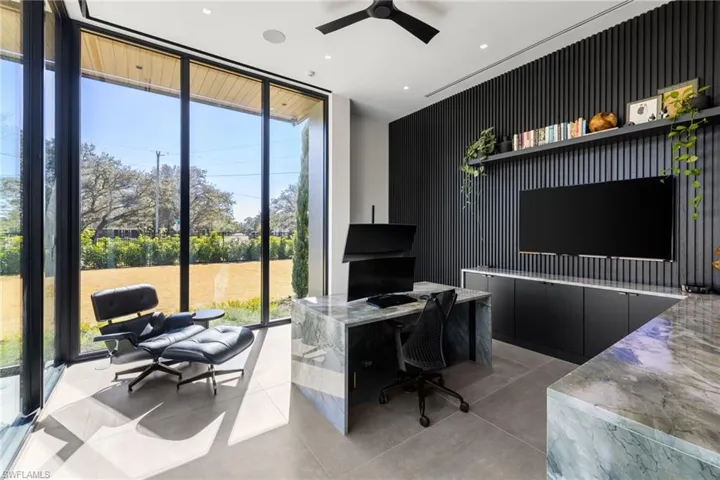 Office area featuring expansive windows and ceiling fan