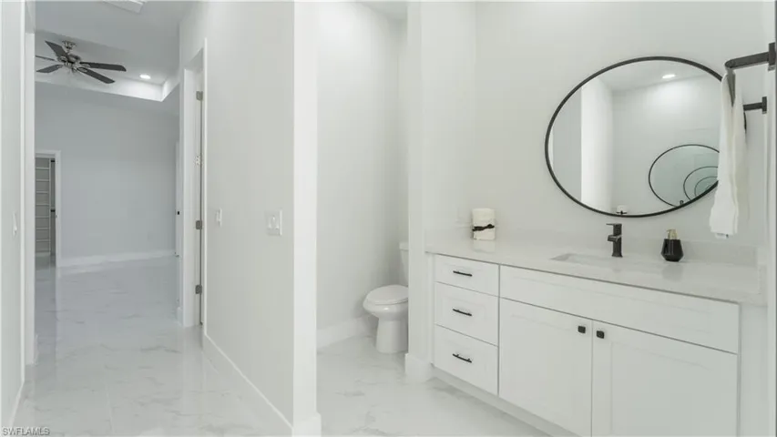 Bathroom with ceiling fan, toilet, and vanity