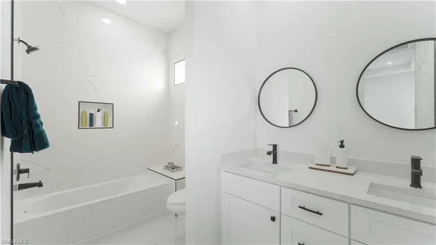 Full bathroom with toilet, tiled shower / bath combo, and vanity