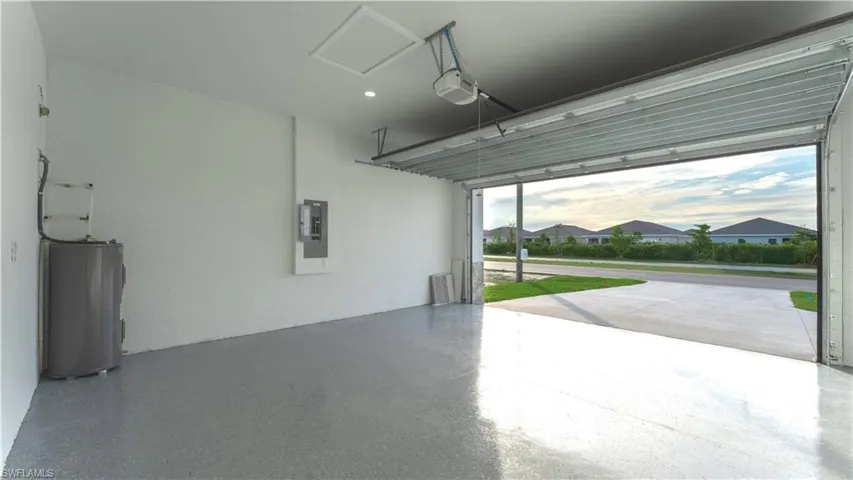 Garage featuring water heater, a garage door opener, and electric panel