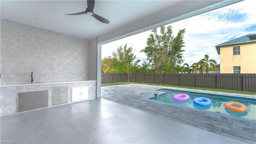 View of pool with ceiling fan, sink, a patio area, and exterior kitchen