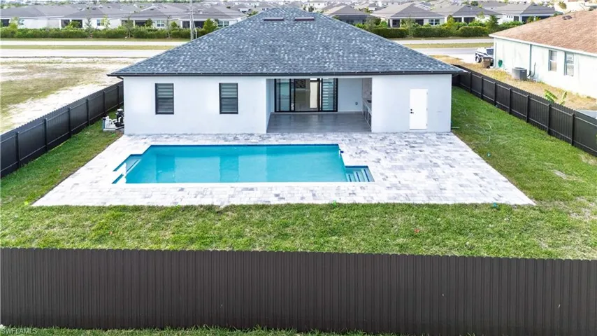 Back of property with a yard, a patio area, and a fenced in pool