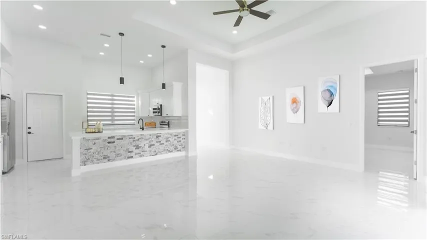 Unfurnished living room with ceiling fan, a healthy amount of sunlight, a tray ceiling, and sink