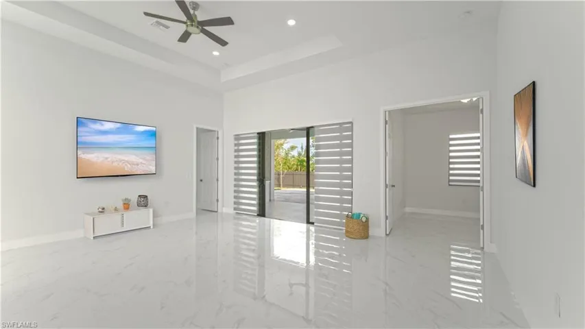 Unfurnished living room featuring a raised ceiling, ceiling fan, and a high ceiling
