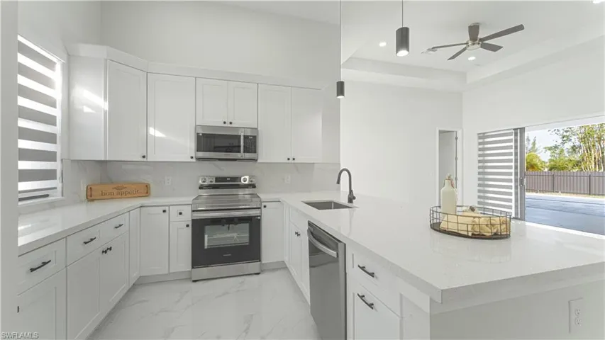 Kitchen with tasteful backsplash, white cabinets, sink, and stainless steel appliances
