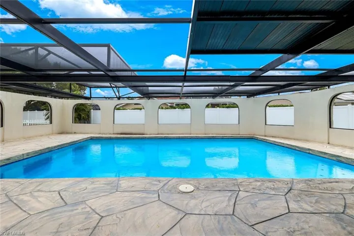 Swimming pool with glass enclosure, a patio, and a sunroom