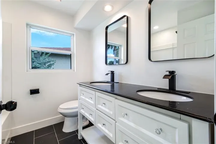 Bathroom with double vanity and dark tile patterned flooring
