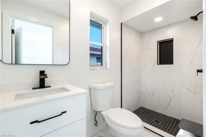 Full bathroom with vanity, a marble finish shower, and recessed lighting