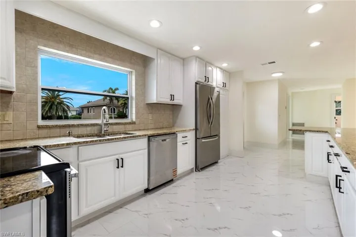 Kitchen featuring stainless steel appliances, light stone countertops, white cabinetry, recessed lighting, and backsplash