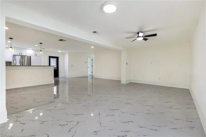 Unfurnished living room featuring light marble finish flooring, recessed lighting, and ceiling fan