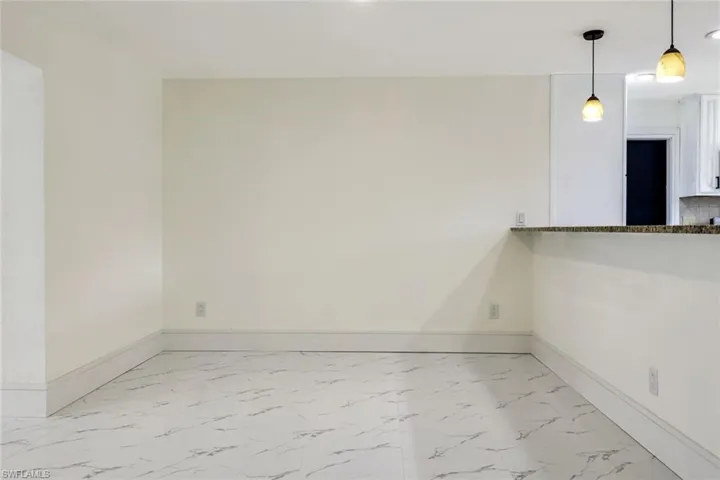 Unfurnished room featuring light marble finish floors and baseboards