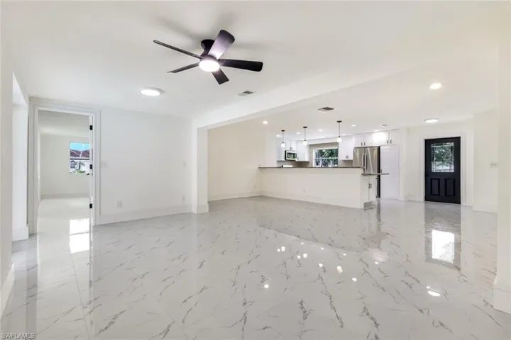 Unfurnished living room with light marble finish flooring, a ceiling fan, and recessed lighting