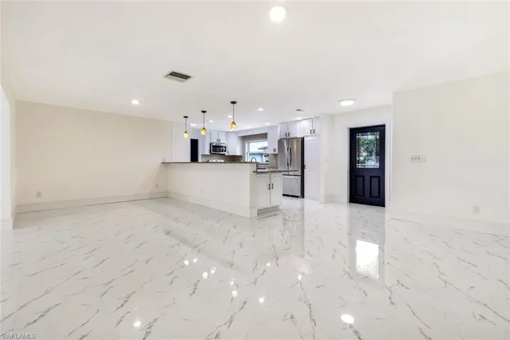Kitchen featuring open floor plan, a peninsula, pendant lighting, recessed lighting, and white cabinetry