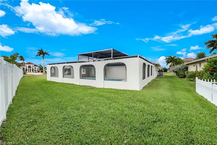 Back of house featuring a fenced backyard, stucco siding, and glass enclosure