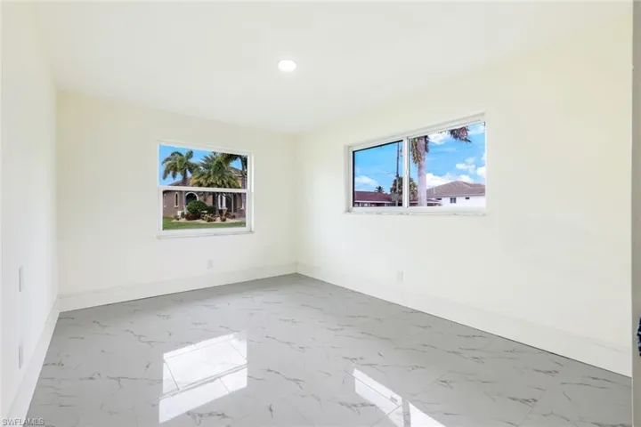 Empty room featuring healthy amount of natural light, light marble finish flooring, and recessed lighting