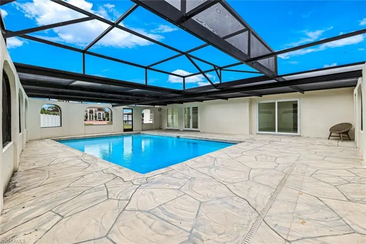Outdoor pool with a sunroom, glass enclosure, a patio area, and french doors