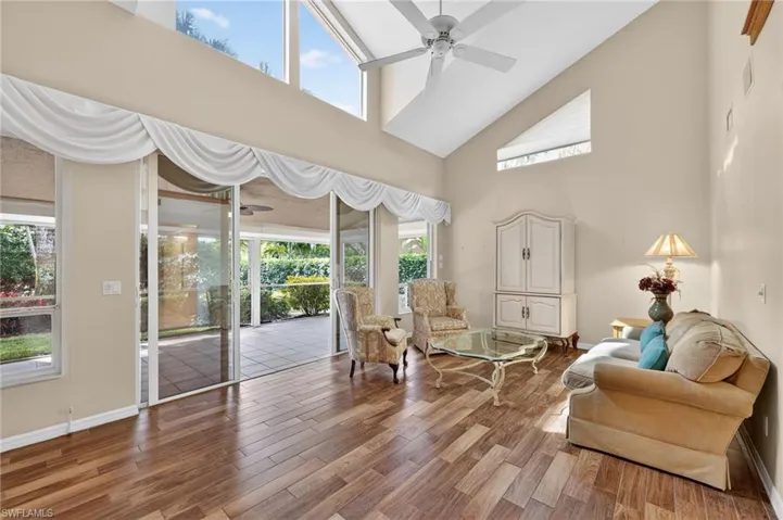 Living area with a ceiling fan, wood-look tile finished floors, and a high ceiling