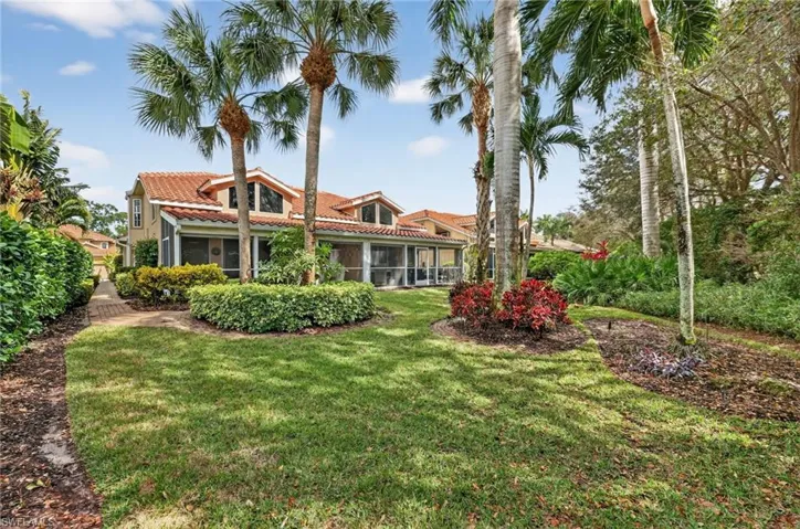 Back of house featuring a tiled roof, a sunroom, a yard, and stucco siding