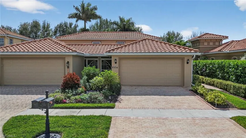Mediterranean / spanish-style house with a garage, stucco siding, a tile roof, and driveway